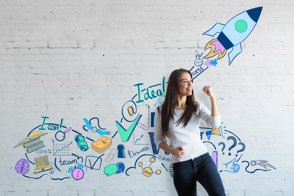 Woman celebrating success on brick wall background with creative drawn space ship
