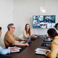 team meeting is captured where colleagues are connected via a large screen