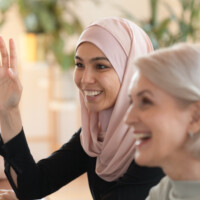 Smiling young Arabian woman raising hand