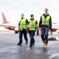 Full Length Of Workers Walking On Wet Runway