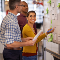 Group of coworkers brainstorming at a whiteboard